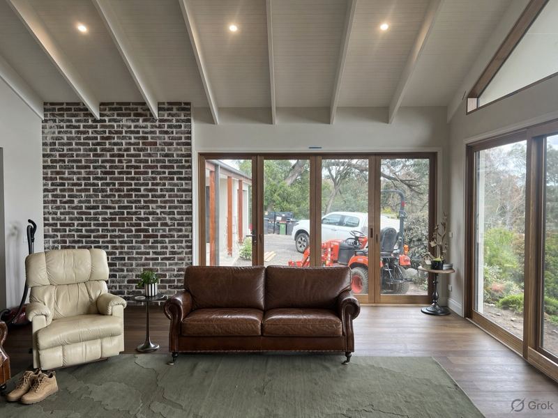 Open living room with a raked white ceiling, recycled brick wall and timber-framed glass doors to the garden